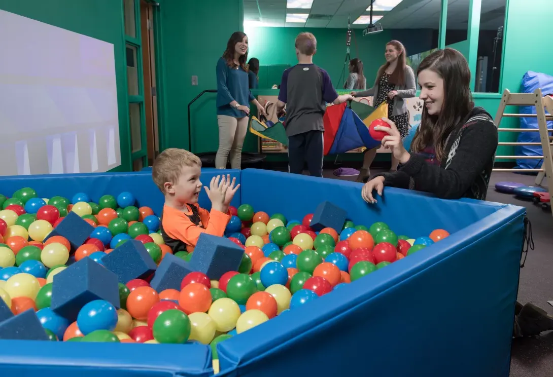 College of Education student works with elementary student in the sensory room ball pit